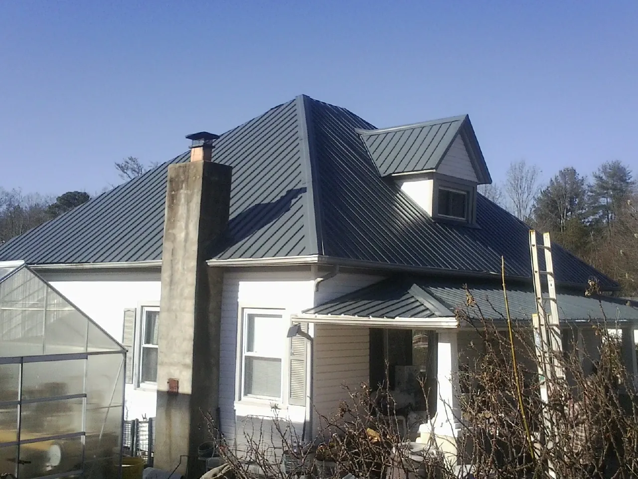 Dark blue standing seam metal roof on a white farmhouse with dormer — Slate & Tile Roof Repair by Roofing Brothers in Duncombe