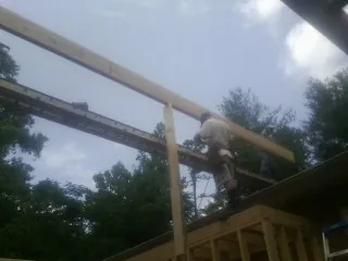 Carpenter setting a ridge beam over a new addition frame — Ice Dam Removal by Roofing Brothers in Duncombe