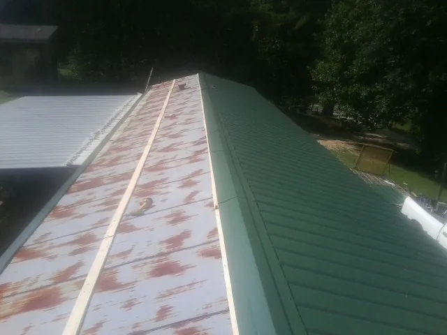 Old rusted panels beside newly installed green metal roofing — Wind Damage Roof Repair by Roofing Brothers in Duncombe