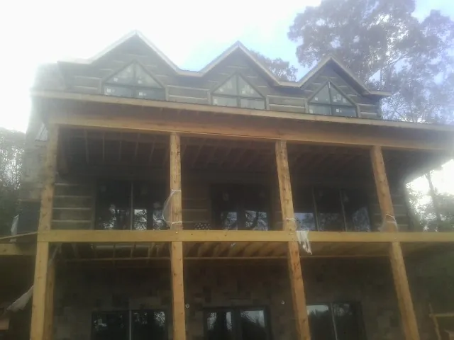 Dormers and porch framing on a large log home under construction — Roof Coating work by our crew in Duncombe
