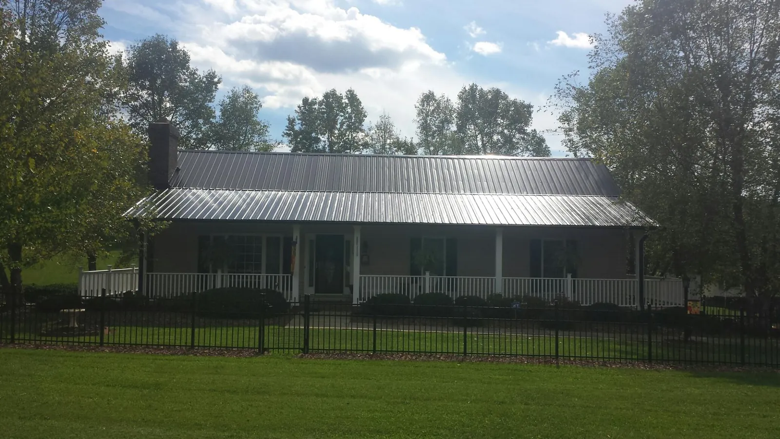 Gray metal roof on a brick ranch with a full width front porch — Gutter Guard Installation work by our crew in Duncombe