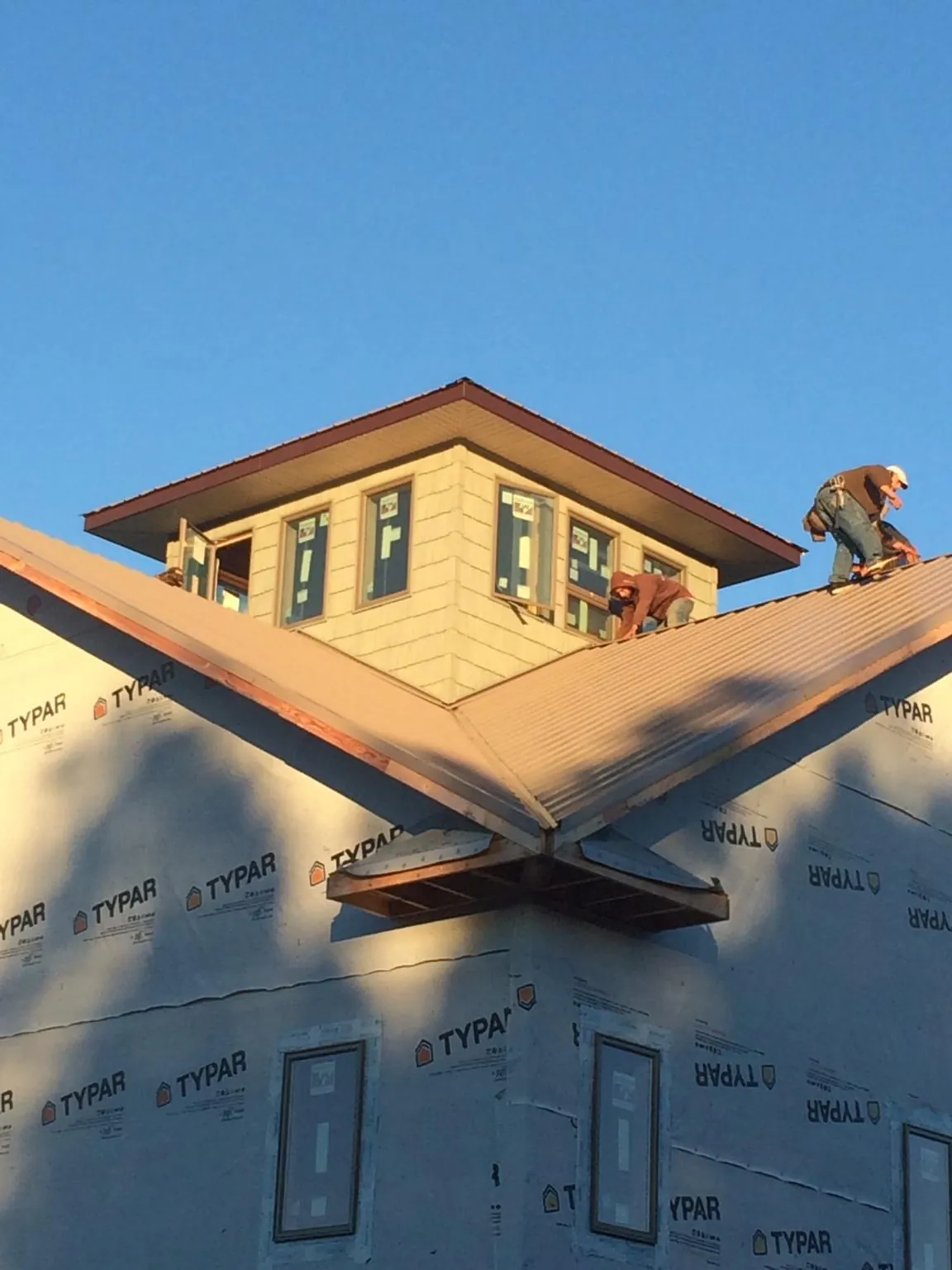 Roofers working around a rooftop cupola on a new metal roof at sunset — Roof Waterproofing in Duncombe by Roofing Brothers